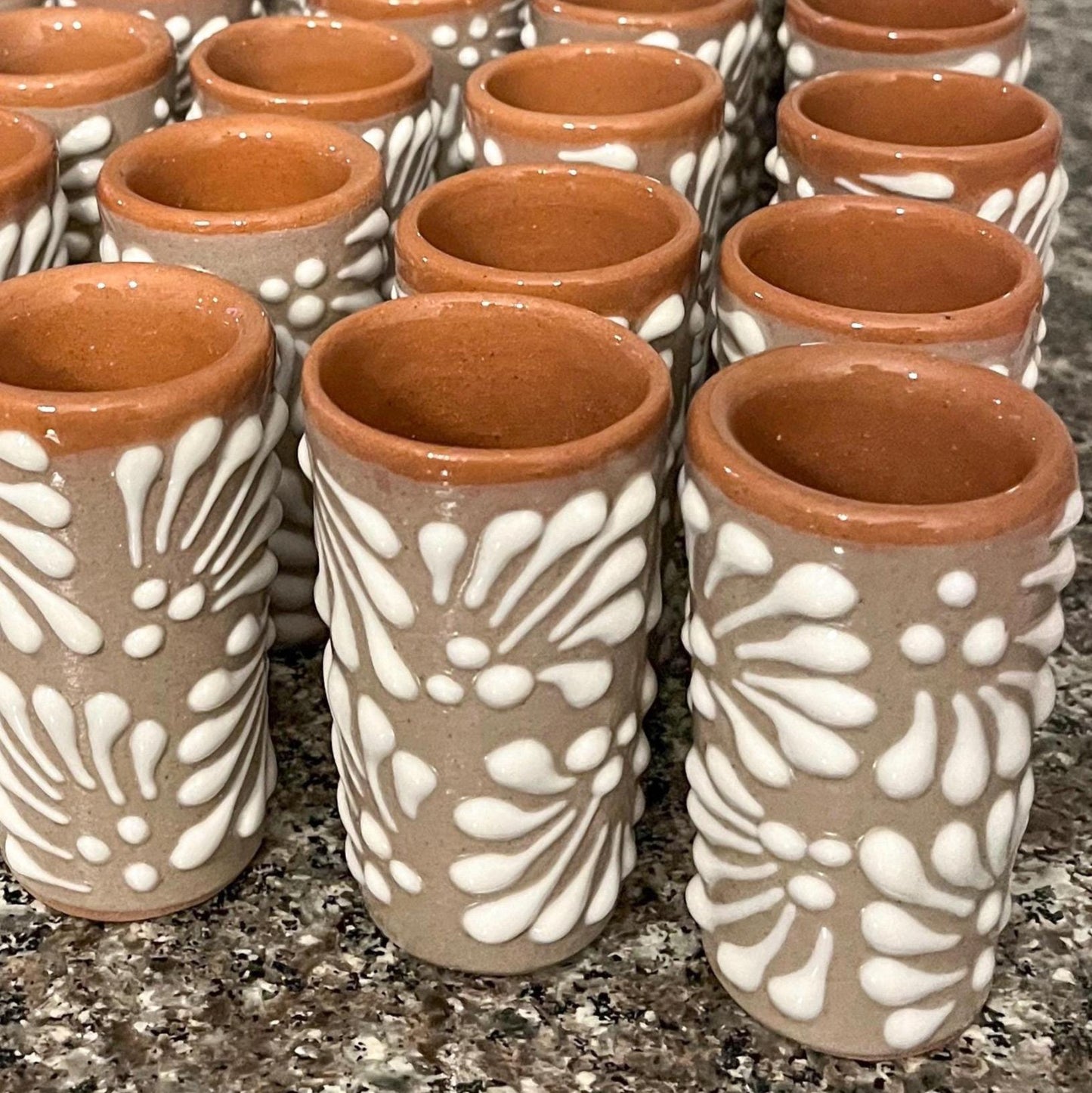 Set of ceramic cups with white patterns on a granite surface