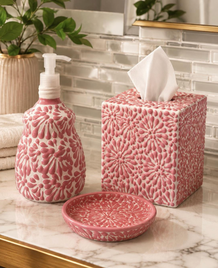 A pink and white floral-patterned bathroom set on a marble countertop, including a tissue box cover, a pump bottle, and a small dish.