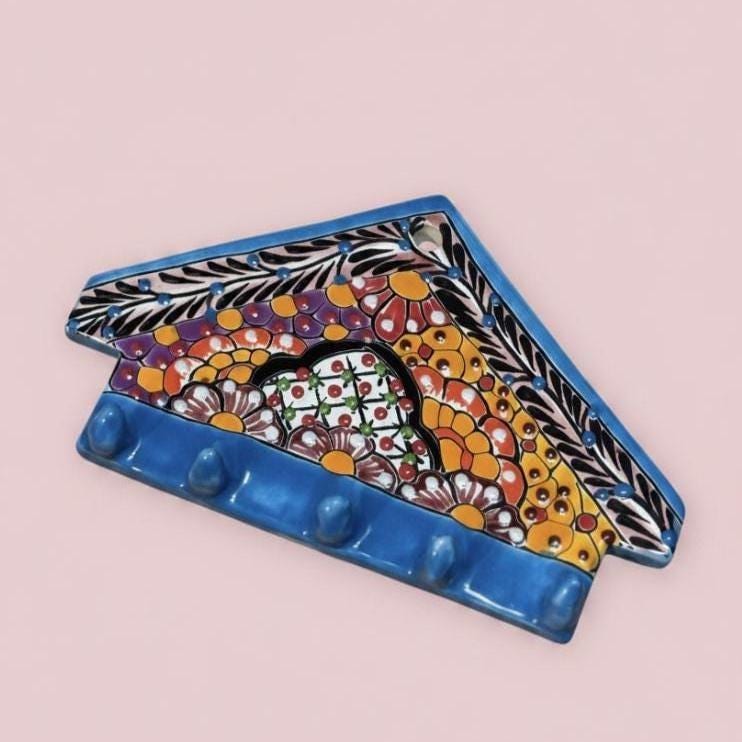 Decorative ceramic wall hook with colorful floral design on a pink background