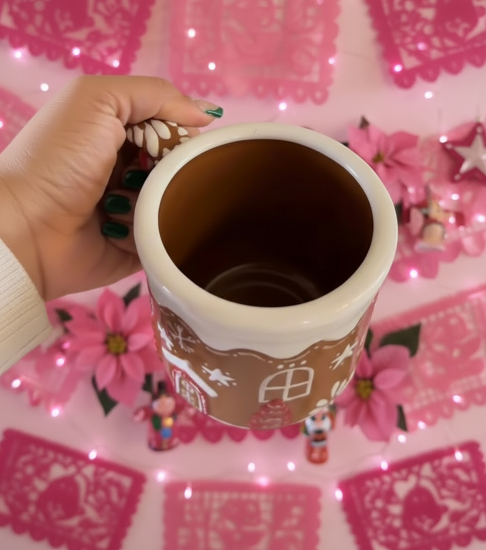 Hand holding a ceramic mug with Christmas-themed design against a blurred Christmas tree background