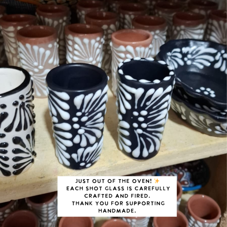 Black and white patterned shot glasses on a wooden shelf with text about handmade craftsmanship.