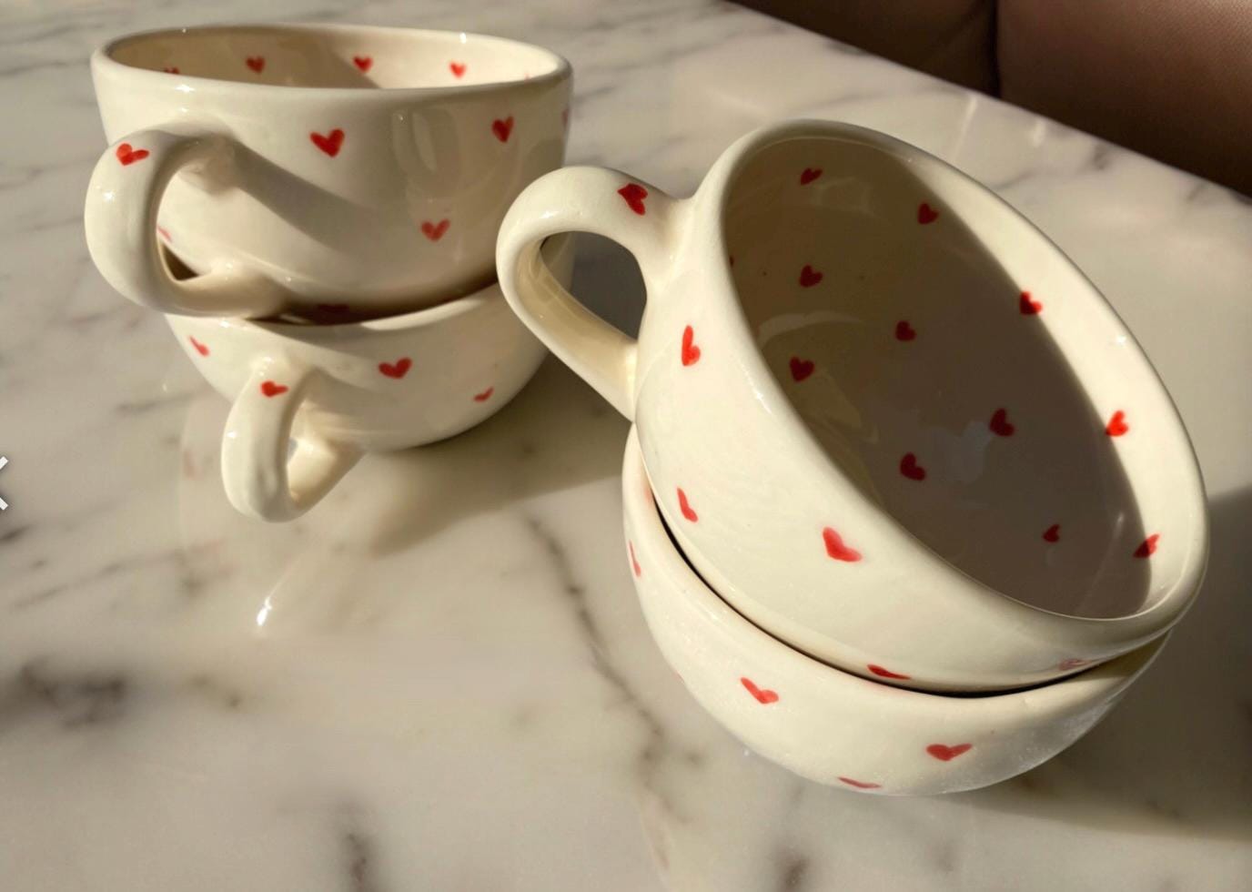 Stacked handmade ceramic heart mugs, set of four showing unique hand-painted designs