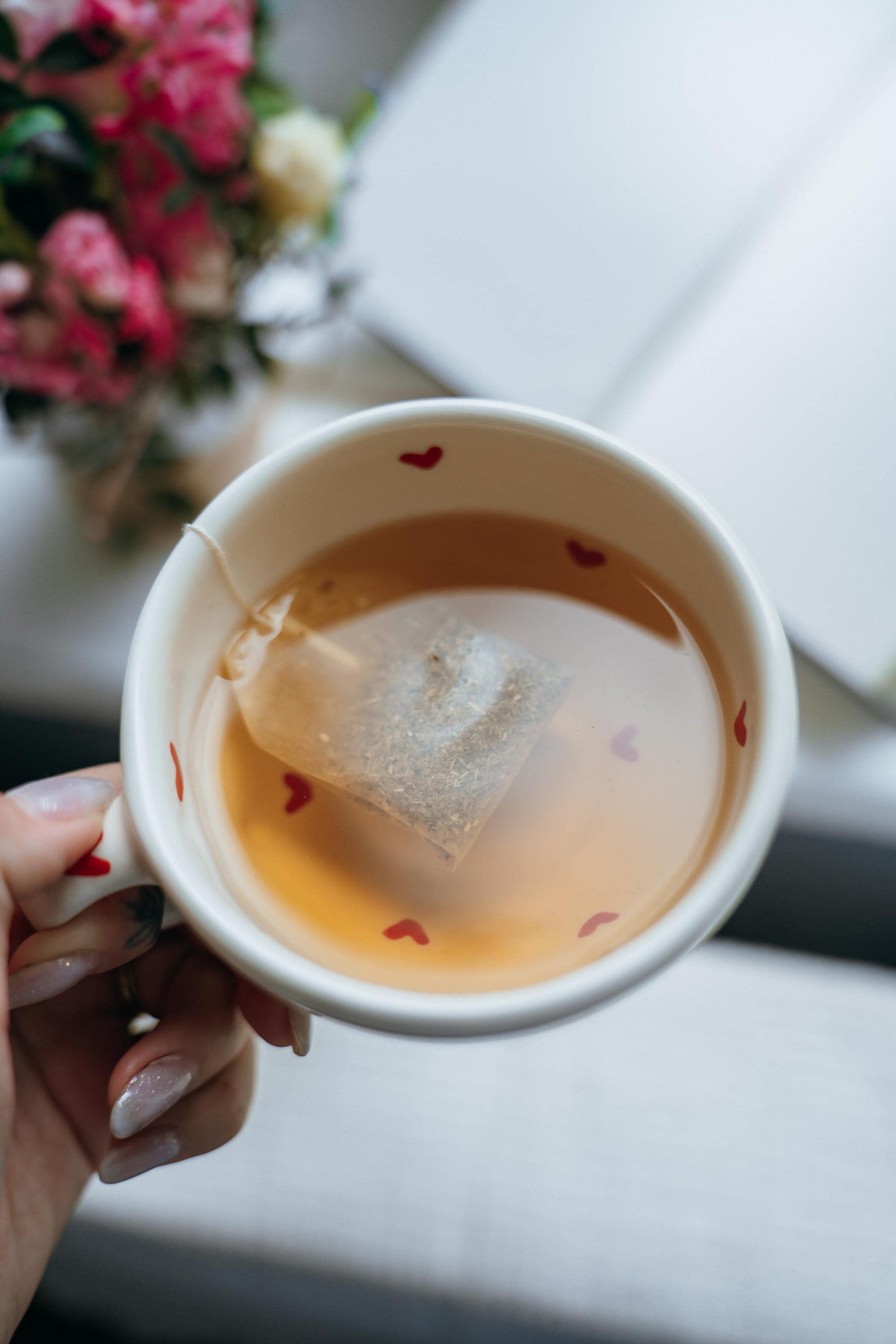 Hand holding handmade ceramic heart mug filled with tea, cozy and warm vibe