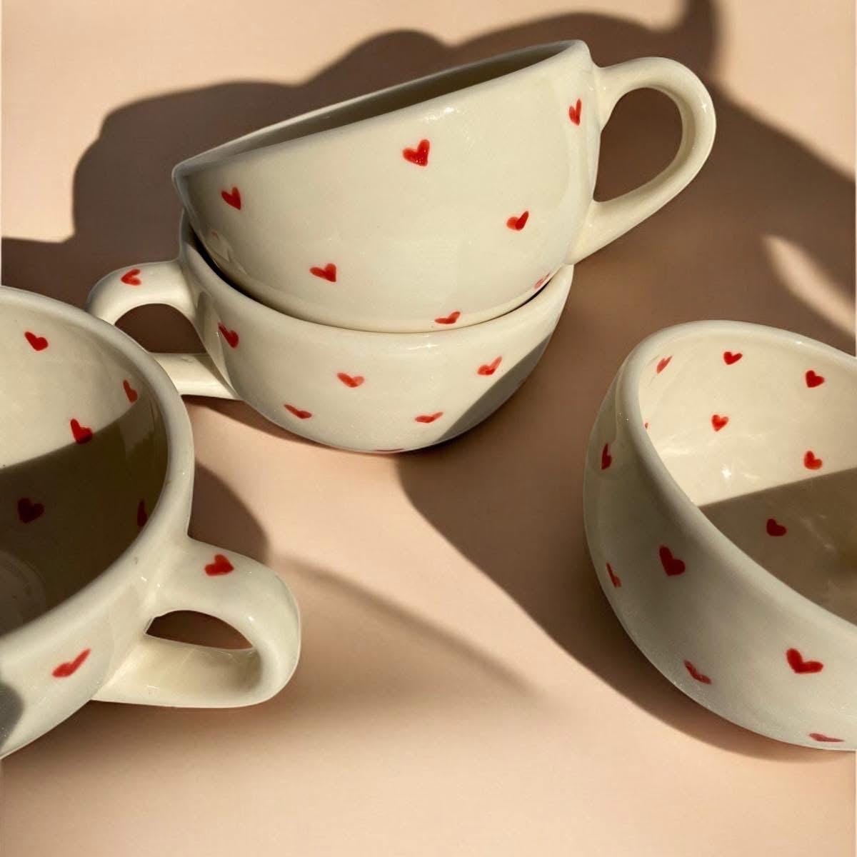 Four handmade ceramic heart mugs with two stacked, light pink neutral background, cozy and aesthetic display