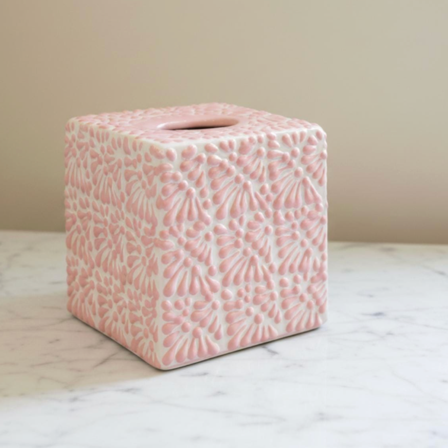 A square pink ceramic tissue box cover with an embossed floral pattern, sitting on a white marble surface against a beige wall.