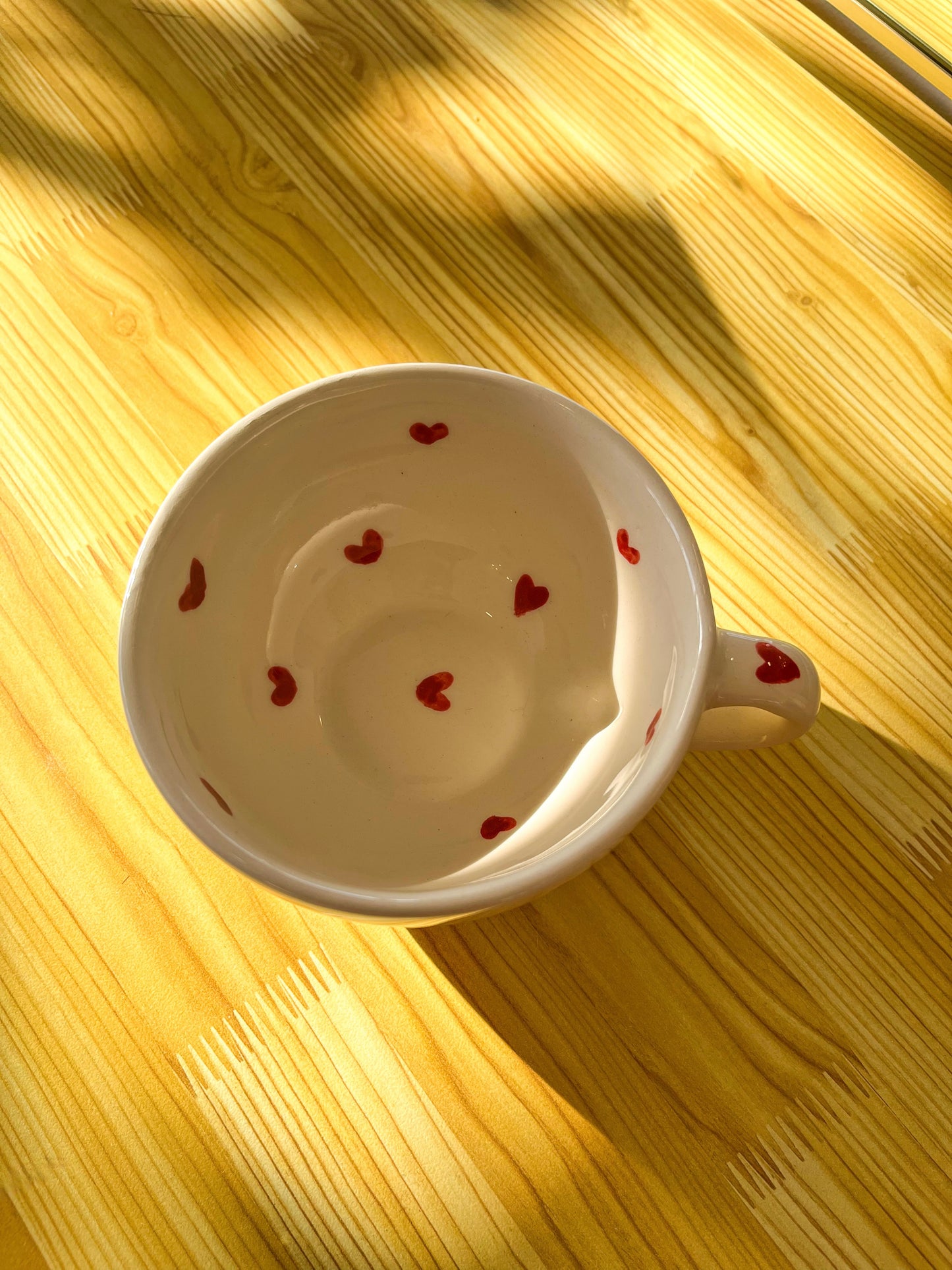 A close-up top view of our charming ceramic mug featuring tiny red hearts. Handmade with love in Mexico.