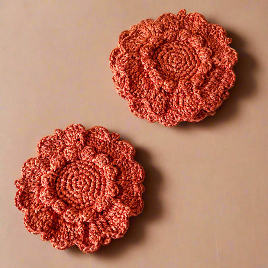Two crocheted flower coasters on a beige background